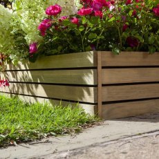 Close-up corner view of Rowlinson Ledbury wooden border edging installed along a gravel path next to a flowerbed.