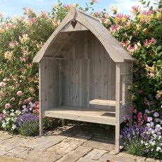 Natural timber Shire Rosewood garden arbour seat with side folding table set on a stone patio with flowering shrubs.