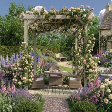 Shire 8x8 wooden pergola featuring climbing white roses, decking floor, and patio table in a cottage garden