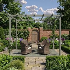 Shire 12x8 wooden garden pergola featuring integrated decking floor and patio chairs set on a paved terrace