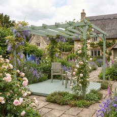 Shire 12x12 wooden garden pergola with integrated decking base and patio dining set in a cottage garden