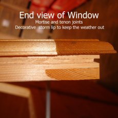 Close-up detail showing the end view of the shed's mortise and tenon joint window frame with a decorative storm lip.