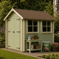 Exterior view of the light green Shire Solway log cabin with two front windows, double doors, and an outdoor potting table set up in a garden.