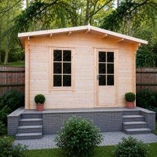 Straight-on exterior view of the Shire Bucknells log cabin showing closed multi-pane glass doors, small potted plants on the steps, and a landscaped backdrop.