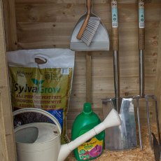 Interior view of garden storage cupboard with hanging tools, compost bag and gardening accessories